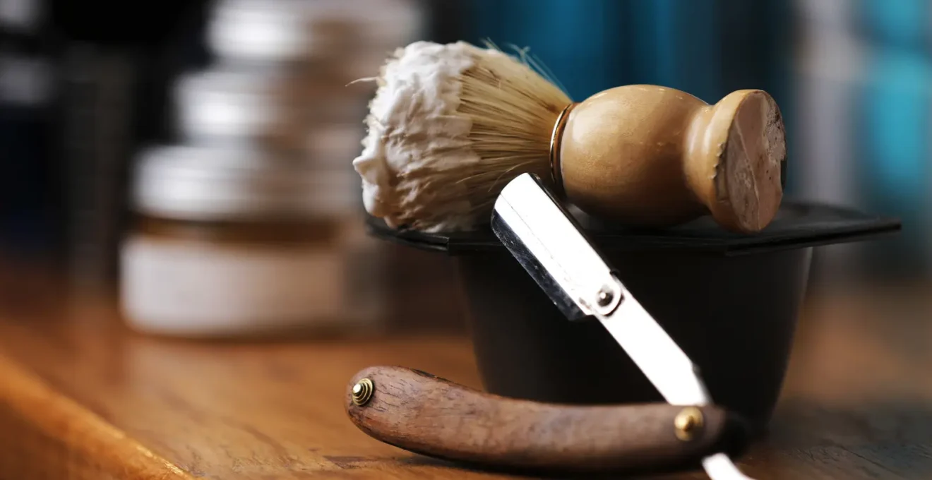 Bol à raser avec mousse montée, blaireau de qualité et serviette disposés sur un plan de marbre blanc