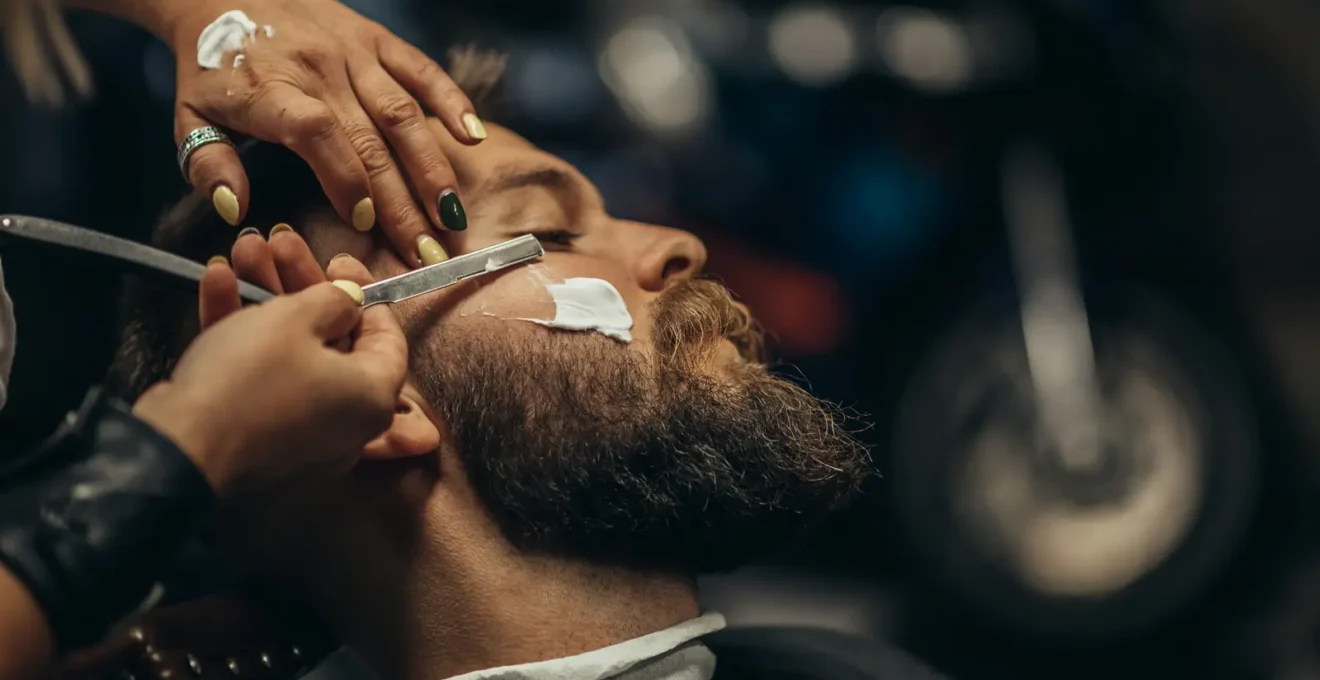 Rasoir coupe-choux traditionnel ouvert posé sur une surface en bois sombre avec des accessoires de rasage classiques