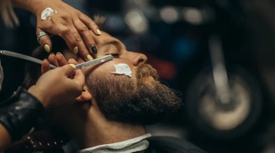 Rasoir coupe-choux traditionnel ouvert posé sur une surface en bois sombre avec des accessoires de rasage classiques